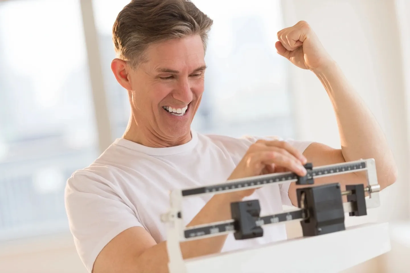 A man is smiling while standing on a scale.